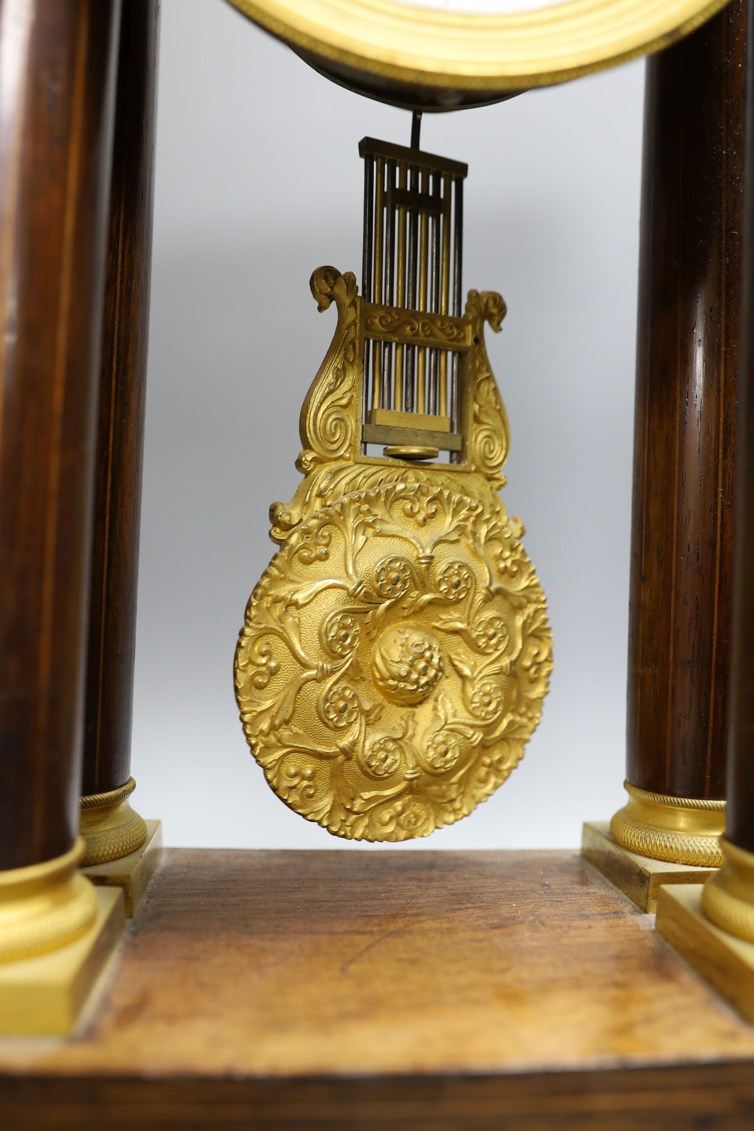 A French rosewood and marquetry portico clock, with pendulum, no key, 44 cms high.